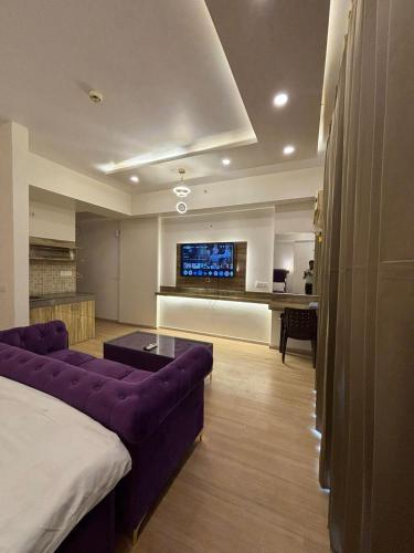 a living room with a purple couch and a tv at The Royal Suites Gomti Nagar Lucknow in Lucknow