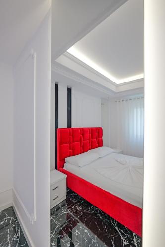 a bed with a red headboard in a white room at New Beach Suite in Sarandë
