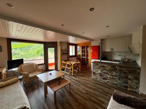 a living room with a couch and a table and a kitchen at Apart Centro Formigal - WOWRURAL in Formigal