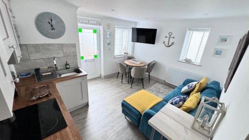 Una sala de estar con un sofá azul y una cocina. en ABOVE PORTHMINSTER BEACH - "St James Rest" is a SUPER STYLISH PRIVATE APARTMENT - 2 mins walk Main Car Park & Station, en St Ives