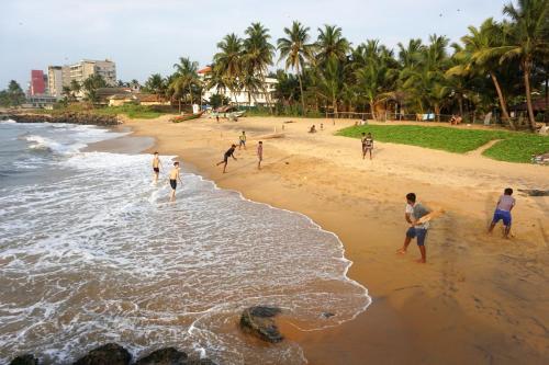 a group of people playing baseball on the beach at Flexi Lodge in Negombo