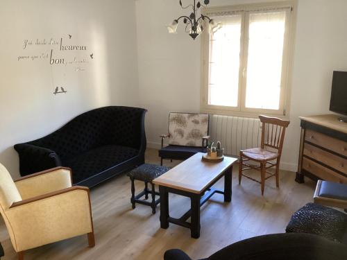 a living room with a couch and chairs and a table at Maison de famille in Écommoy