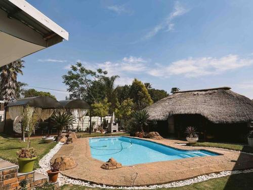 una piscina in un cortile con un edificio con il tetto di paglia di Elegant Poolside Retreat 2-Bed Luxury Guesthouse a Newcastle