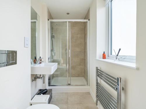 een badkamer met een douche, een toilet en een wastafel bij Pass the Keys Bright modern flat wparking in Addlestone