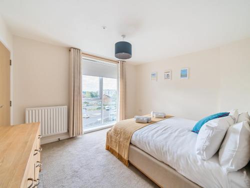 a bedroom with a bed and a large window at Pass the Keys Bright modern flat wparking in Addlestone