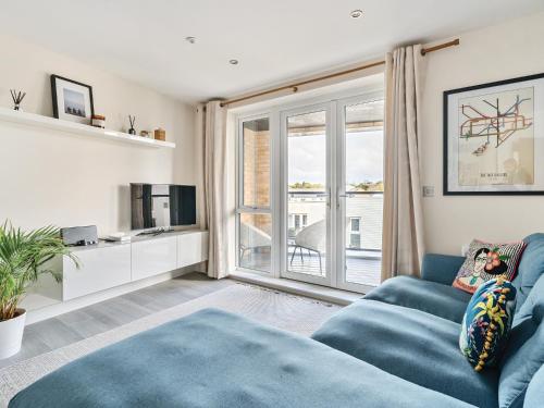 een woonkamer met een blauwe bank en een raam bij Pass the Keys Bright modern flat wparking in Addlestone