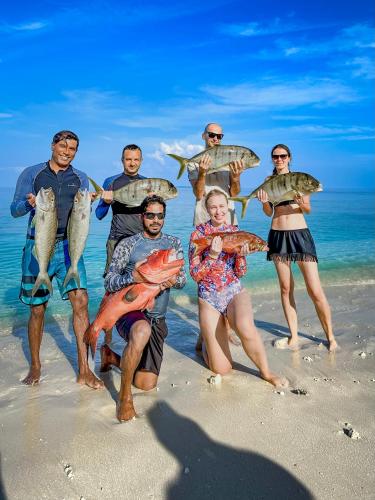 a group of people holding fish on the beach at Sabba Summer Suite , Fodhdhoo in Fodhdhoo