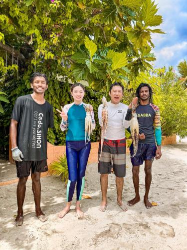 a group of four people standing on the beach at Sabba Summer Suite , Fodhdhoo in Fodhdhoo