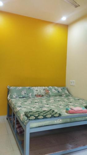 a bed in a room with a yellow wall at आंगण होम स्टे in Malvan