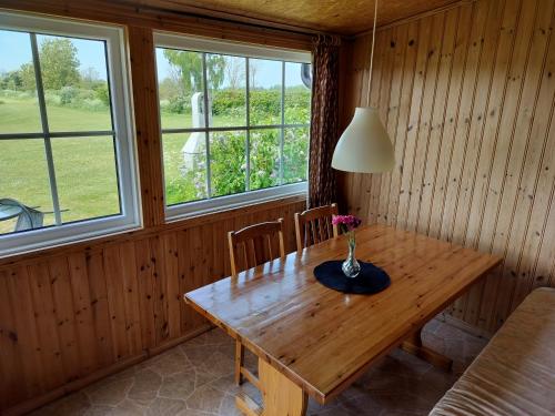 ein Esszimmer mit einem Holztisch und 2 Fenstern in der Unterkunft Svalsjöns Stugor Öland in Köpingsvik