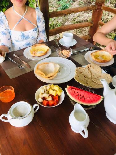 Una donna seduta a un tavolo con piatti di cibo di Ella Jungle Cottage a Ella