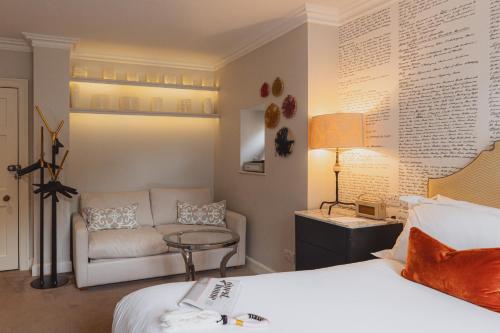 a bedroom with a bed and a couch and a table at No 15 by GuestHouse, Bath in Bath