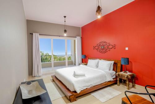 a bedroom with a large bed and a red wall at Live surrounded by gorgeous Green Golf fields in Ras al Khaimah