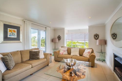 a living room with two couches and a fireplace at Pezula 's Paradise in the Sun - No Loadshedding in Knysna