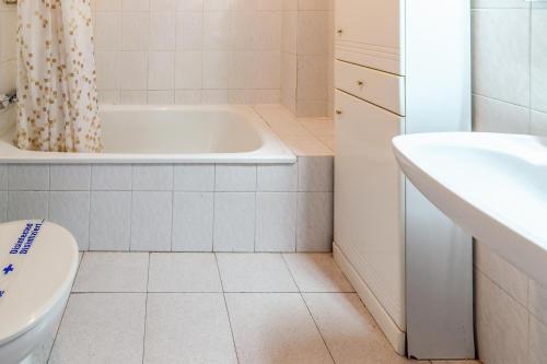een badkamer met een bad, een toilet en een wastafel bij Fener de Dalt 84 apartamento piscina comunitaria in Llança