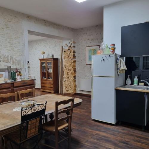 une cuisine avec une table et un réfrigérateur blanc dans l'établissement Chez Peta - maison familiale rénovée 100m², à Fontaine-le-Comte