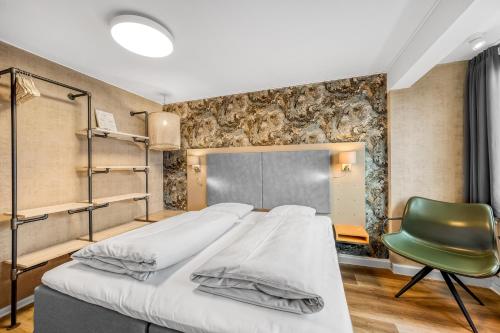 a bedroom with a bed and a green chair at Hvide Sande Hotel in Hvide Sande