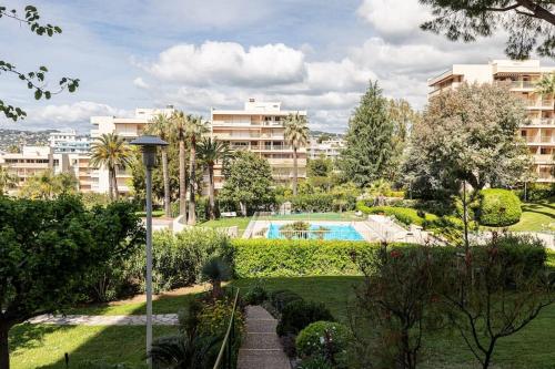- une vue sur un parc avec une piscine et des bâtiments dans l'établissement Elegant 2 Bed Apt with Pool in Juan Les Pins, à Antibes