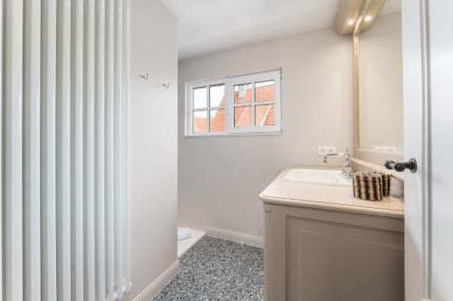 a bathroom with a sink and a window at Villa Manouchka - Verblijf in alle luxe aan zee in De Haan