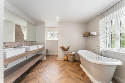 a white bathroom with two sinks and a tub at Villa Manouchka - Verblijf in alle luxe aan zee in De Haan