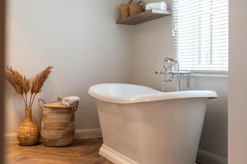 a white bath tub in a bathroom with a window at Villa Manouchka - Verblijf in alle luxe aan zee in De Haan