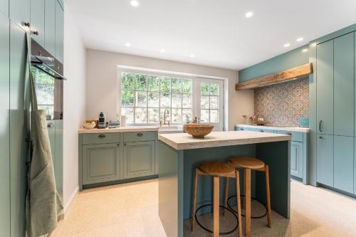 a kitchen with blue cabinets and a counter with stools at Villa Manouchka - Verblijf in alle luxe aan zee in De Haan