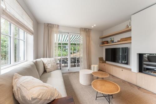 a living room with a couch and a tv at Villa Manouchka - Verblijf in alle luxe aan zee in De Haan