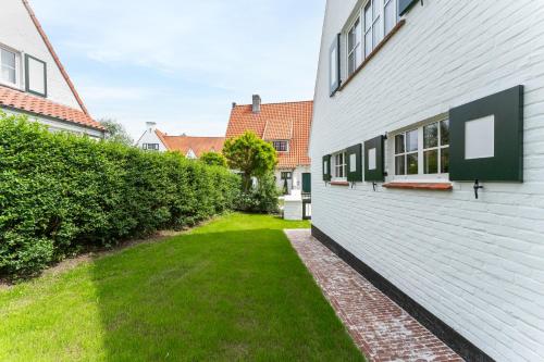an empty yard next to a white building at Villa Manouchka - Verblijf in alle luxe aan zee in De Haan