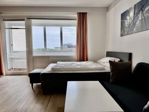 Cette chambre comprend un lit, un canapé et une fenêtre. dans l'établissement Haus Atlantic Whg. 514, à Cuxhaven