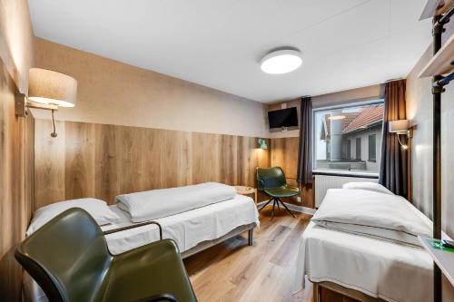 una habitación de hospital con 2 camas y una silla en Hvide Sande Hotel, en Hvide Sande