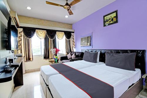 1 dormitorio con 1 cama grande y paredes moradas en OYO Flagship Hotel Night Owl, en Durgāpur