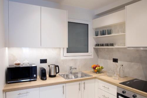 a kitchen with white cabinets and a sink and a microwave at La Residence Athens in Athens