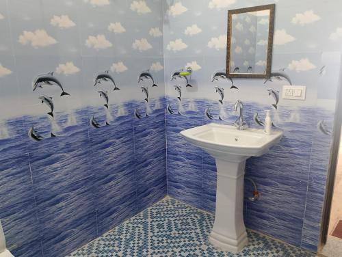 a bathroom with a sink and birds on the wall at Cherry Binhar, Matogi in Kāta Patthar