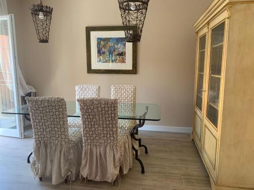 Un comedor con una mesa de cristal y sillas. en Central luxury rooms, en Olbia
