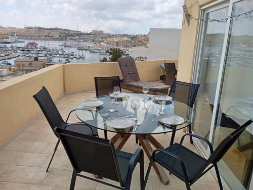 a table and chairs on a balcony with a view of a harbor at MIVE Luxury Sea View Penthouse in Il-Gżira