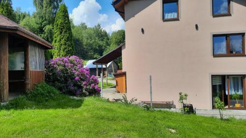 a house with purple flowers next to a yard at Pokoje u Juroszka in Istebna