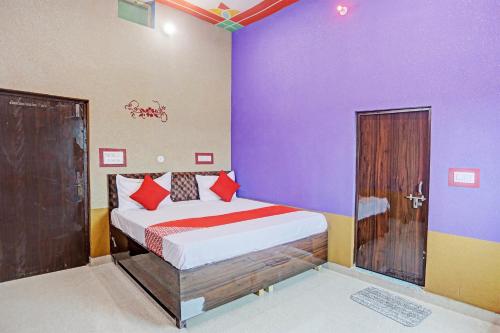 a bedroom with a bed with purple walls at Hotel O Dwarka in Alīgarh