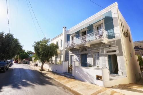a white building with a balcony on a street at STEMA Kalymnos in Kalymnos