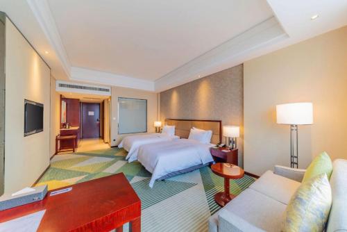 a hotel room with two beds and a couch at Holiday Inn Foshan Nanhai Central by IHG in Foshan