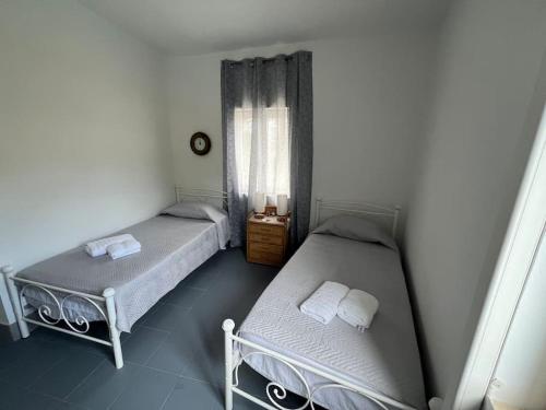 two twin beds in a room with a window at La casa sulle rocce House on the rocks in Asos