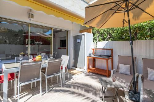 un patio avec une table et un parasol dans l'établissement Superbe studio bord de mer avec terrasse & piscine, à Cannes