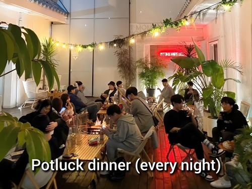 a group of people sitting at tables in a restaurant at Mido Hostel in Seogwipo