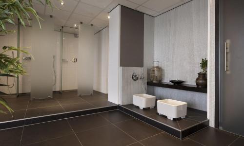 a bathroom with two white toilets and a shower at Van der Valk Hotel Sassenheim - Leiden in Sassenheim