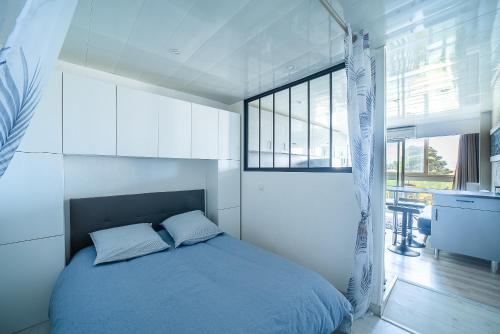 une chambre avec un lit bleu dans une pièce blanche dans l'établissement L'Abri Côtier Radieux - Plage à 5min à pied, à Canet