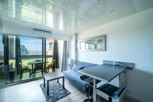 un salon avec un canapé bleu et une table dans l'établissement L'Abri Côtier Radieux - Plage à 5min à pied, à Canet