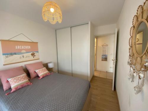 - une chambre avec un lit doté d'oreillers roses et d'un miroir dans l'établissement Appartement de charme T3 avec petit jardin et parking, à La Teste-de-Buch