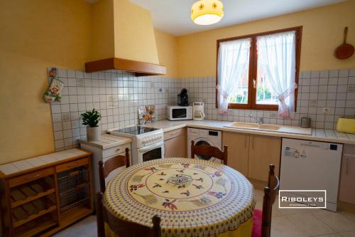 une cuisine avec une table, un évier et une cuisinière dans l'établissement Maison climatisée avec grand jardin ombragé, à Vias
