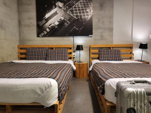 a bedroom with two beds and a suitcase at Mido Hostel in Seogwipo