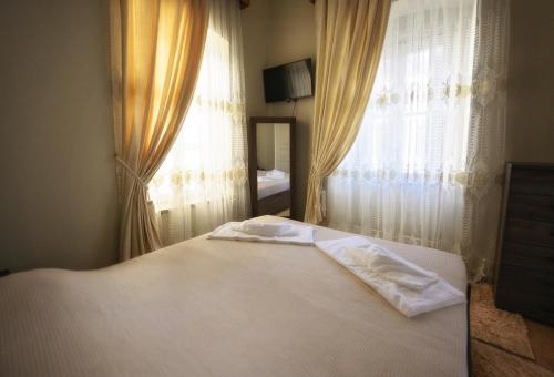 a bedroom with a white bed with curtains and a window at STEMA Kalymnos in Kalymnos