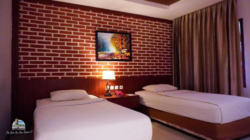 een slaapkamer met 2 bedden en een bakstenen muur bij Watu Dodol Hotel & Restaurant in Banyuwangi
